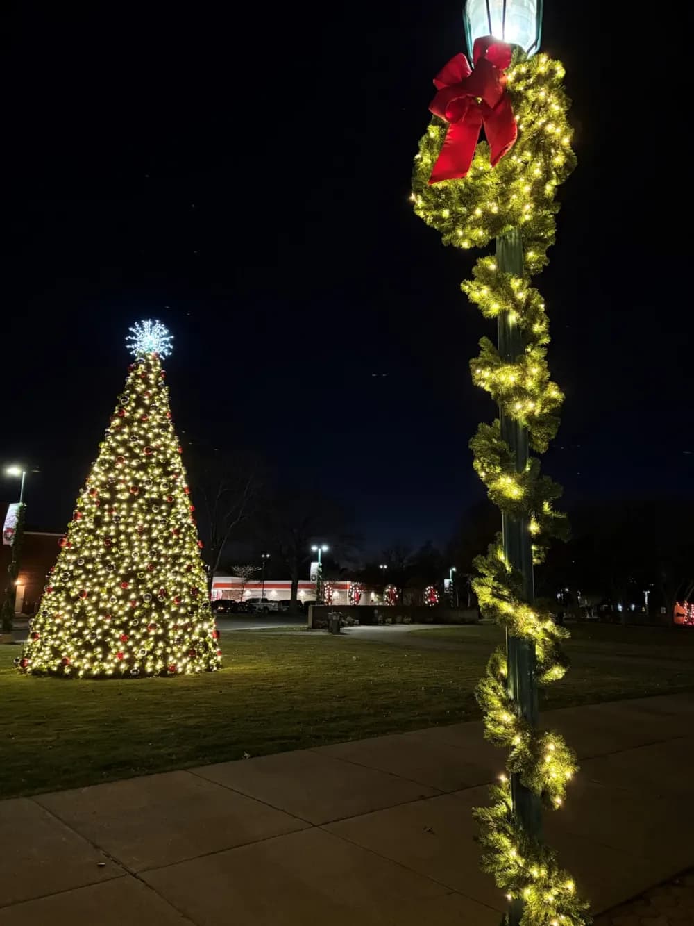 Lit garland pole wrap and street-light décor on a downtown street
