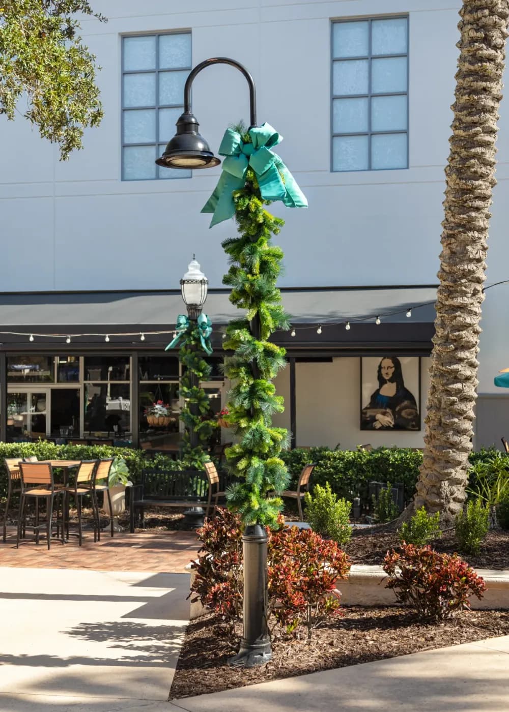 Lit garland pole wrap and street-light décor on a downtown street