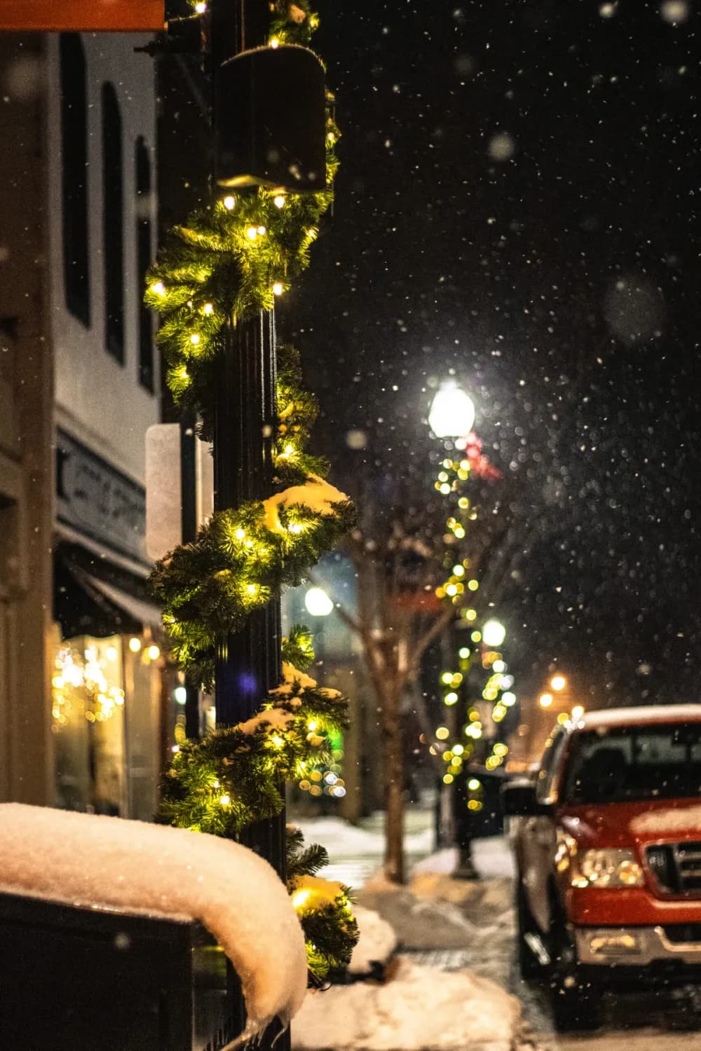 Lit garland pole wrap and street-light décor on a downtown street